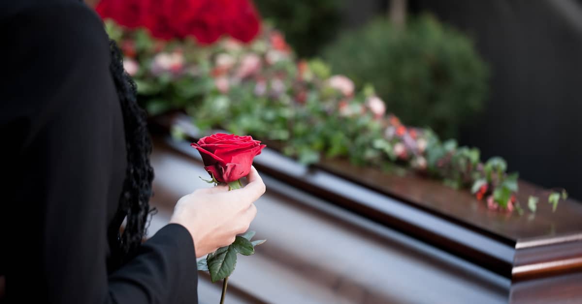 Woman's hand holding rose over casket | Colling Gilbert Wright