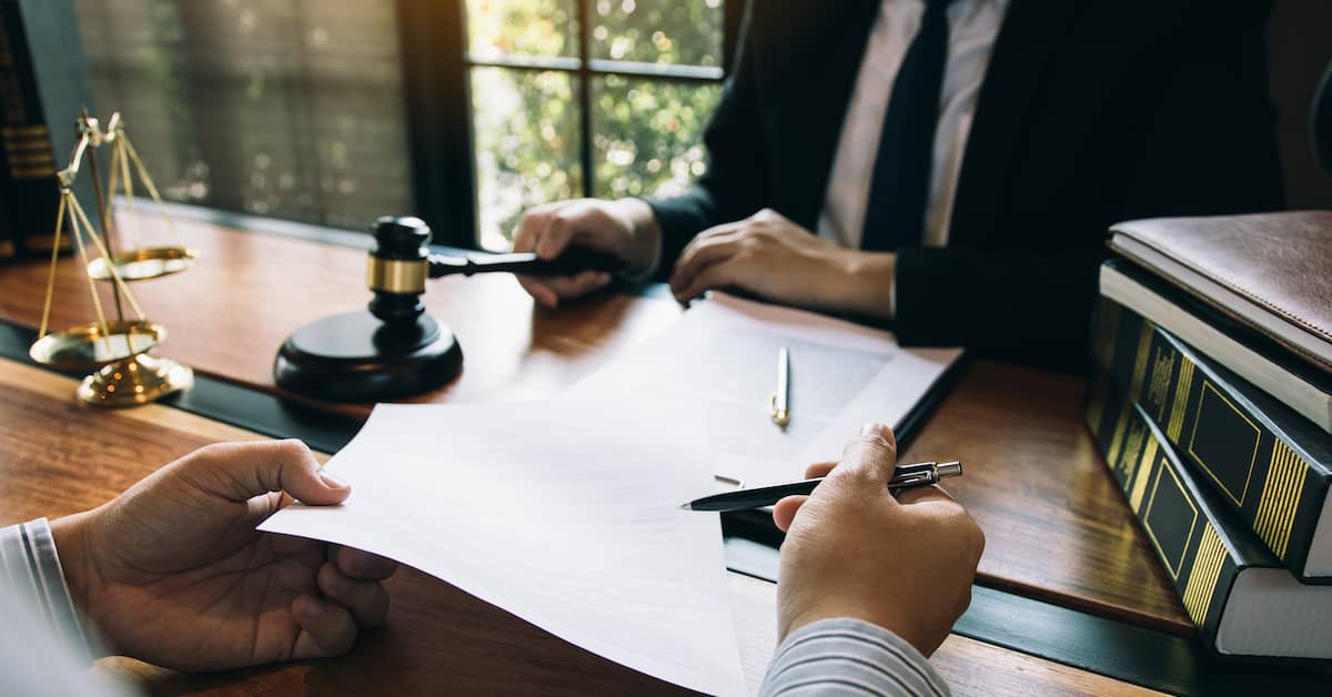 Hands of a judge and lawyer talking at desk. | Colling Gilbert Wright