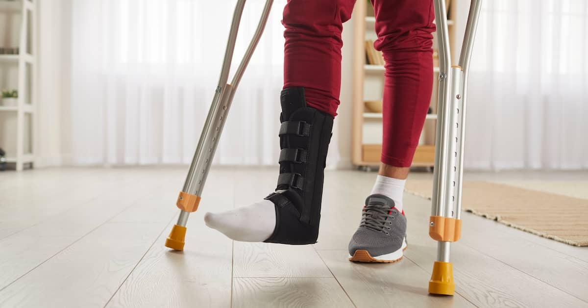 Legs of a man with one injured on crutches. | Colling Gilbert Wright