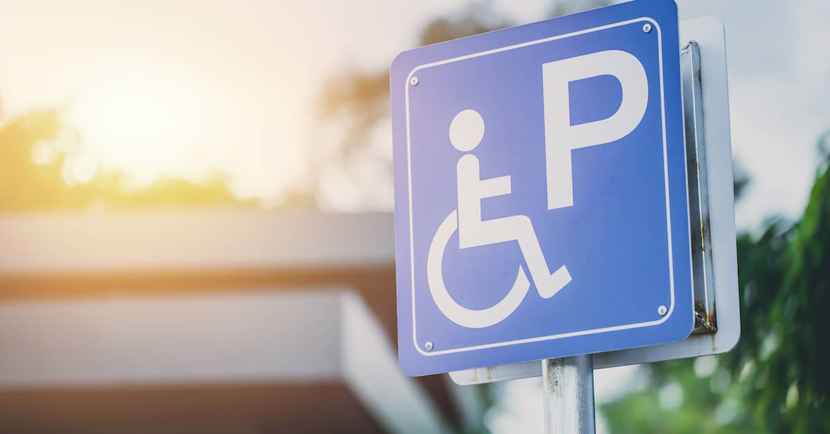a handicap sign stands in front of a building | Colling Gilbert Wright