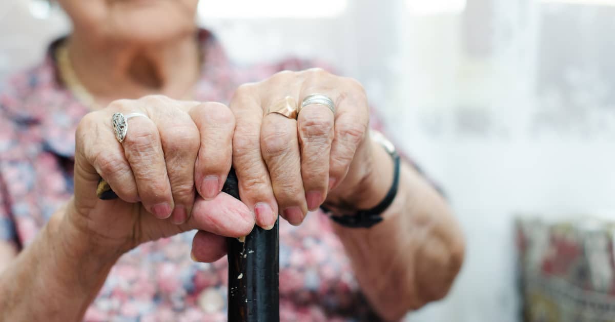 An older woman's hands gripping her cane.