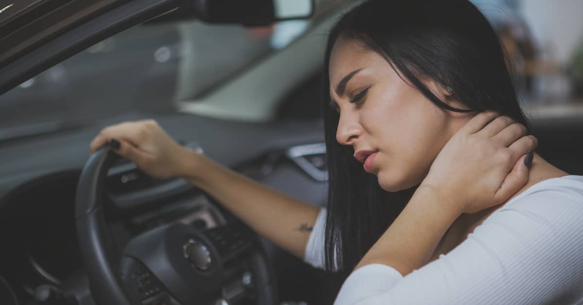 Woman in driver's seat holding neck after a car accident. | Colling Gilbert Wright