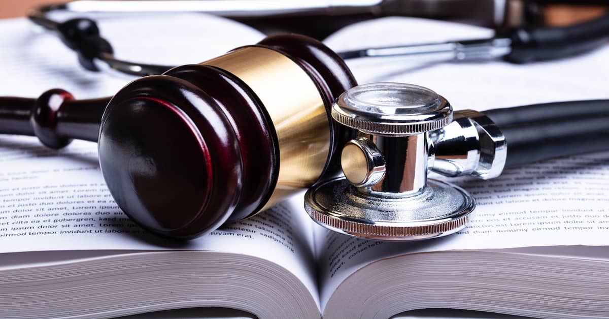 A gavel and a stethoscope on a medical malpractice law book. | Colling Gilbert Wright