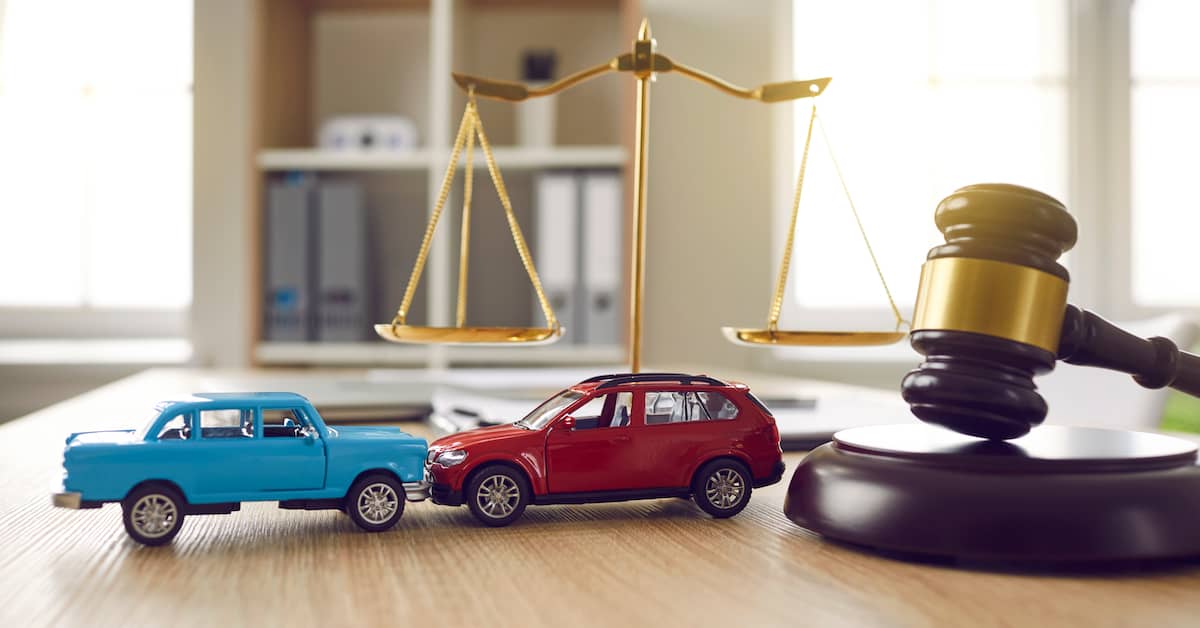 Two toy cars in accident next to gavel and scales. | Colling Gilbert Wright