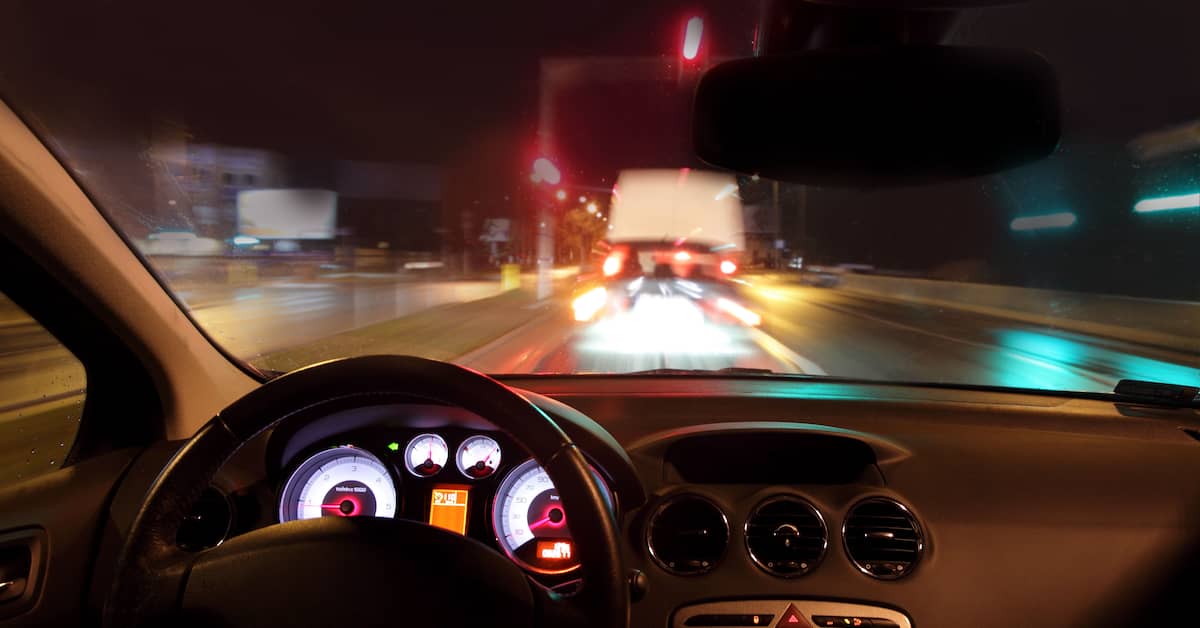 Looking through the windshield of a car on the road at night. | Colling Gilbert Wright