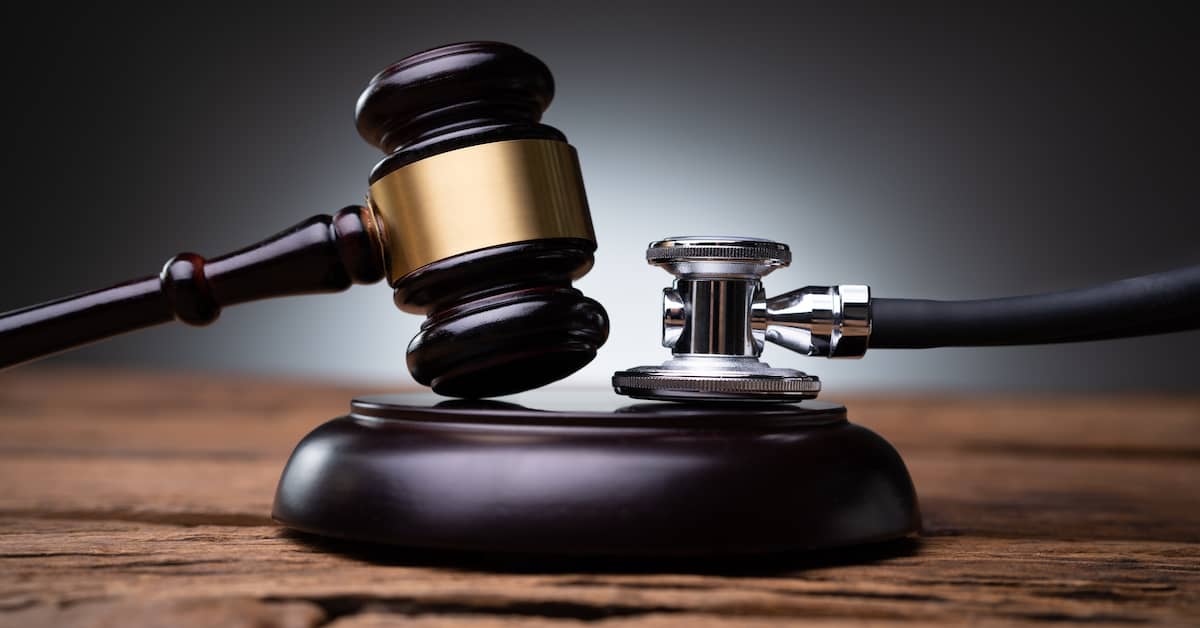 Judge's gavel and stethoscope on a desk. | Colling Gilbert Wright